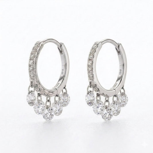 A pair of silver hoop earrings with small clear diamonds along the front and five clear dangling round diamonds stones on each earring, shown on a white background.