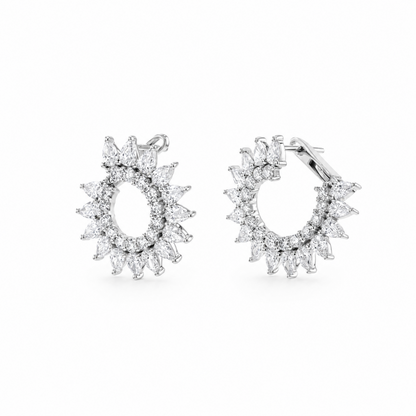 A pair of silver hoop earrings with marquise-cut clear  diamonds. arranged in a sunburst or flower-like halo design, shown on a plain white background.