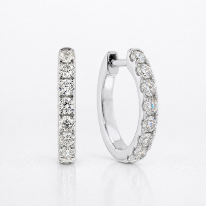 A pair of silver hoop earrings with a single row of round-cut clear diamonds, shown on a clean white background.
