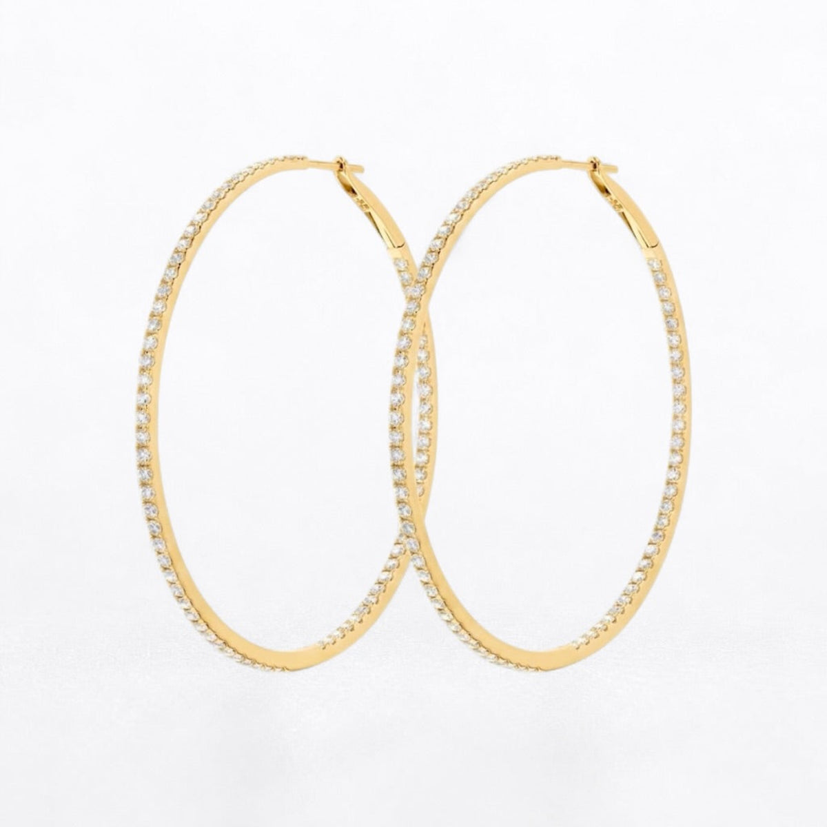 A pair of gold hoop earrings embellished with small clear diamonds along the outer edges, displayed on a clean white background.