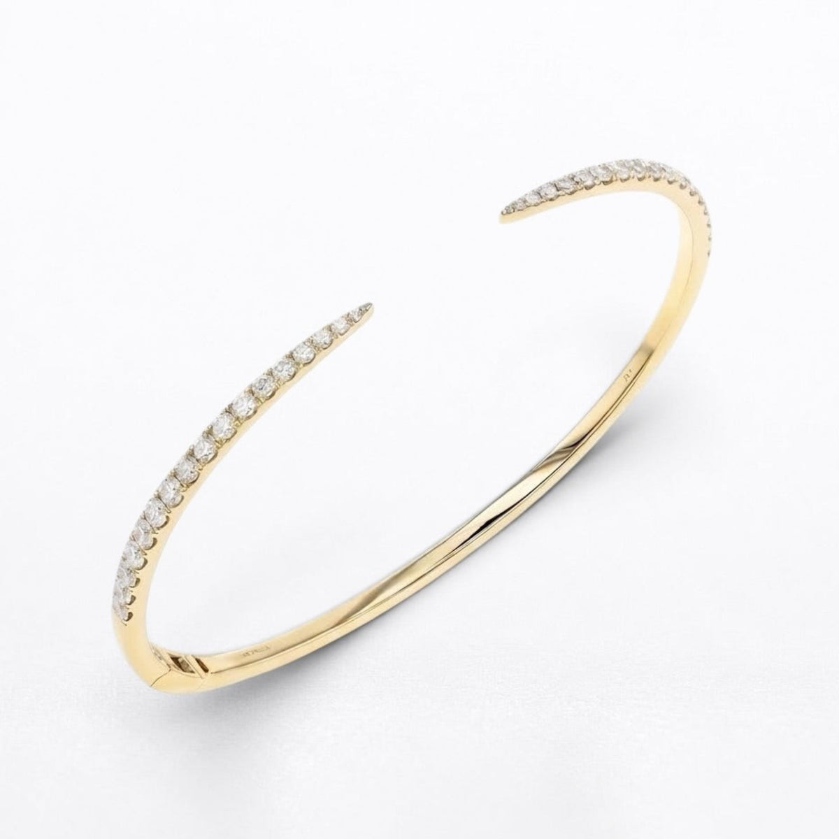 A slim open cuff bangle bracelet in yellow gold, featuring rows of small clear pavé diamonds along both open ends, photographed on a clean white background.