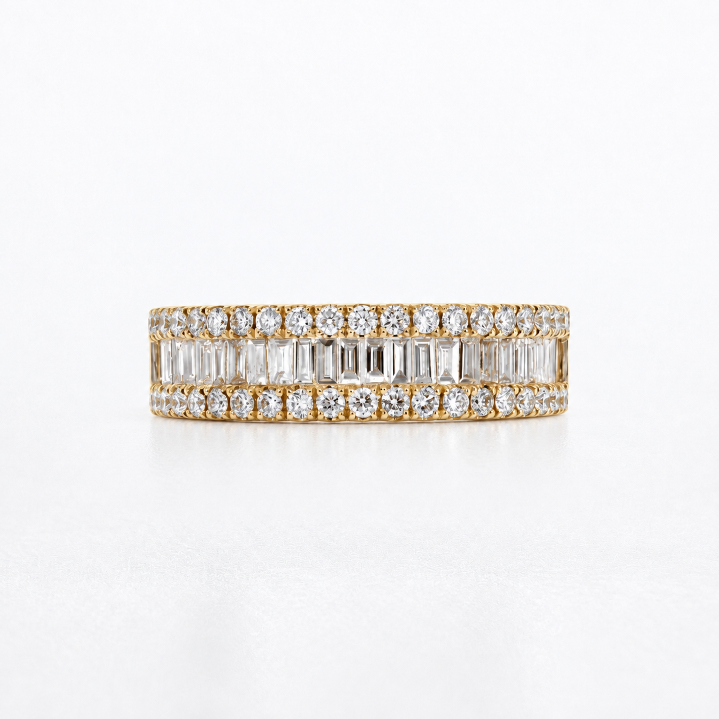 A yellow gold eternity ring featuring double rows of baguette and round-cut clear diamonds, photographed on a clean white background.