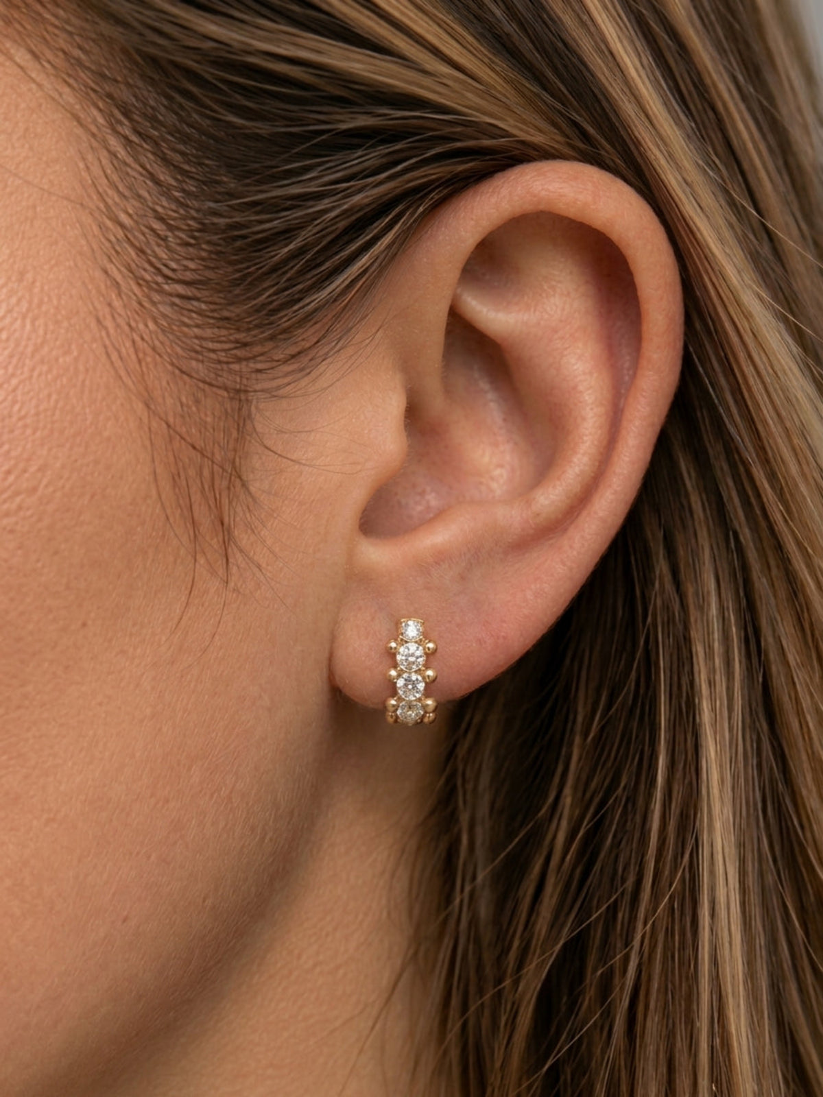 Close-up of model wearing 10mm Orbi natural diamond bezel and gold bead huggie earring in 18K yellow gold