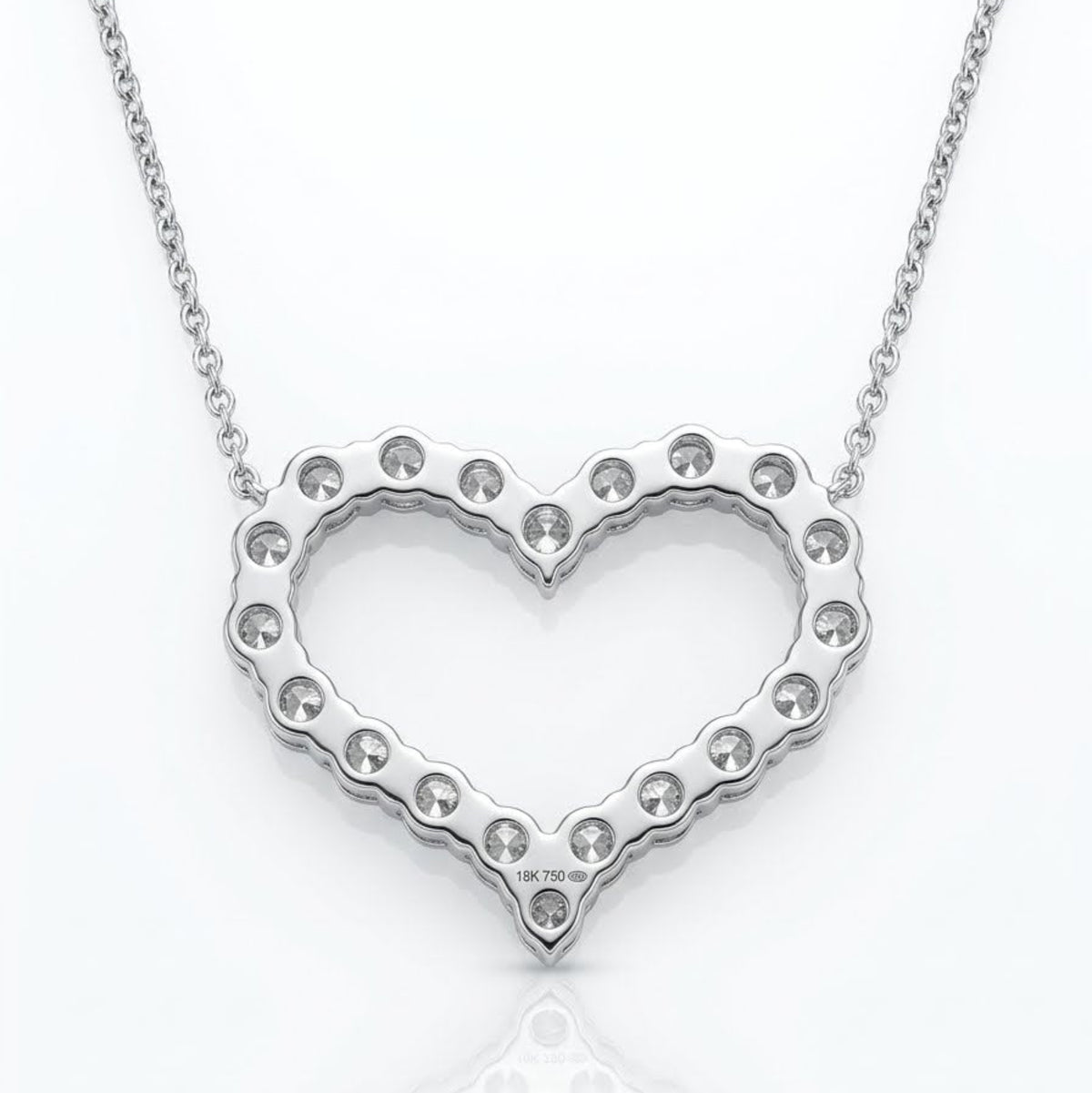 A silver heart-shaped pendant necklace with a scalloped edge and small clear rhinestones, suspended from a delicate silver chain on a white background with a soft reflection.