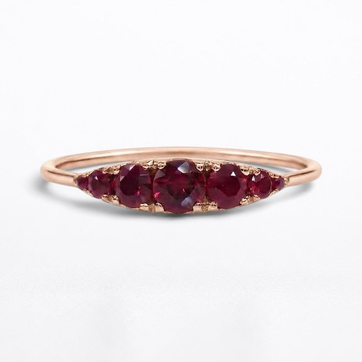 Low profile 14K rose gold arc ring with seven graduated natural rubies