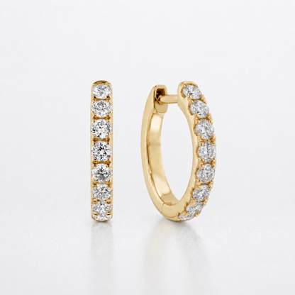 A pair of gold huggie hoop earrings with a channel-set row of round diamonds, shown on a clean white background.
