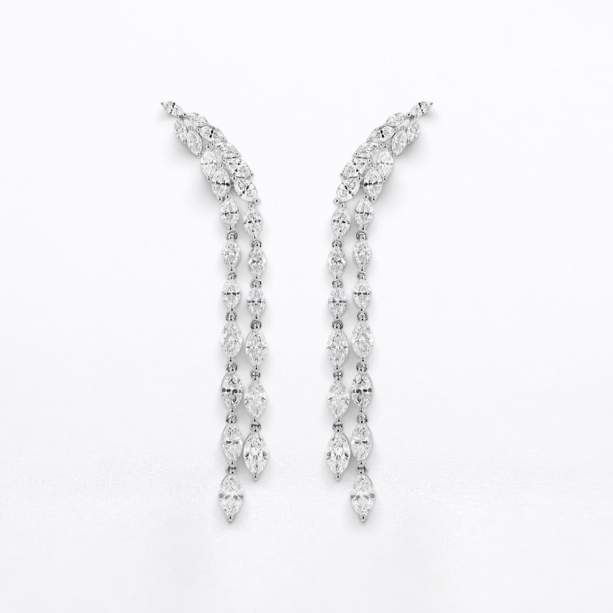 A pair of silver-tone drop earrings adorned with marquise diamonds, arranged symmetrically on a plain white background.