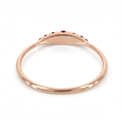A rose gold signet ring with a small row of red ruby along the top curve, shown on a clean white background.
