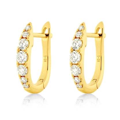 A pair of yellow gold huggie hoop earrings, each adorned with a row of round-cut clear diamonds , shown on a clean white background with a soft reflection below.