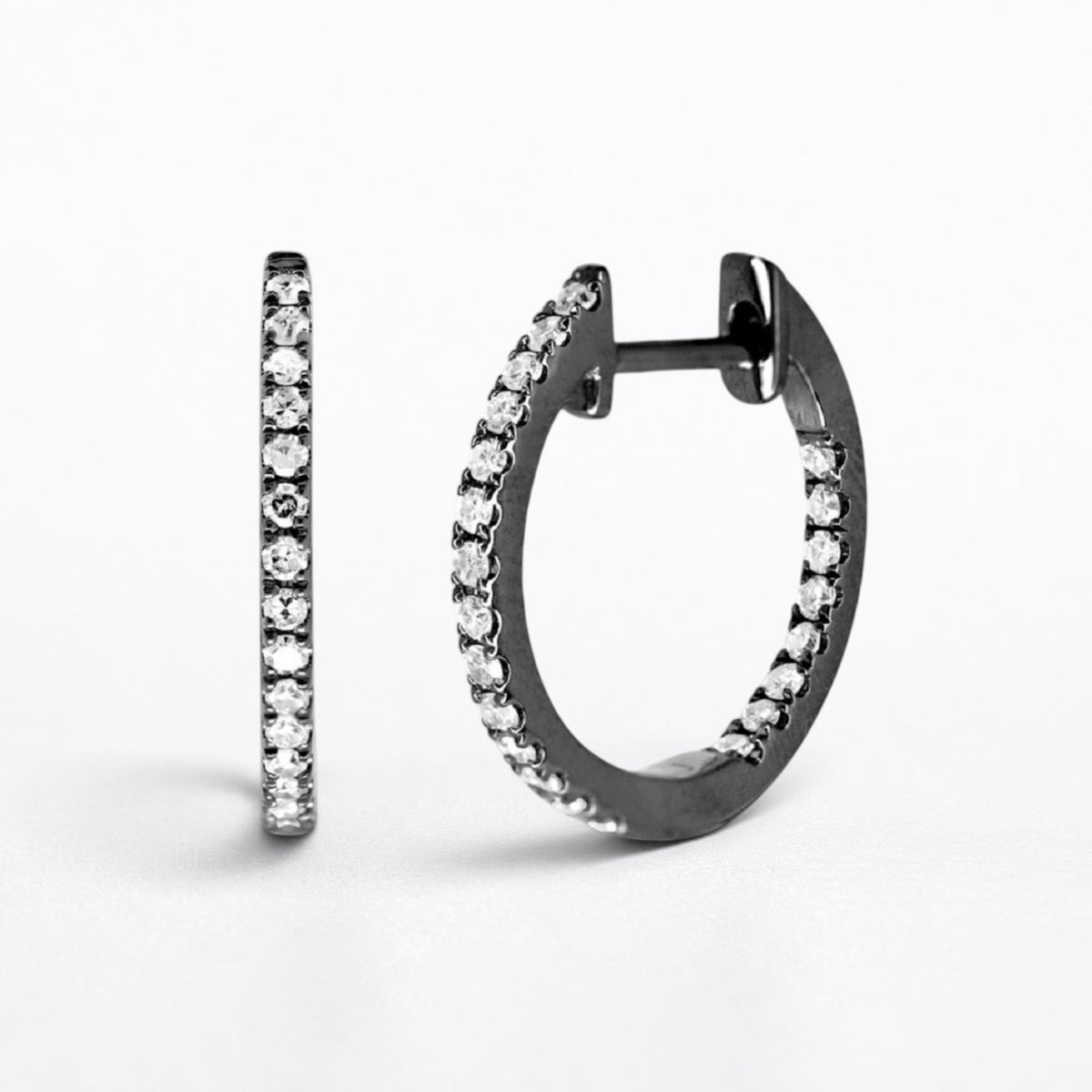 A pair of small hoop earrings with a dark metal finish and rows of clear diamonds, shown on a clean white background.