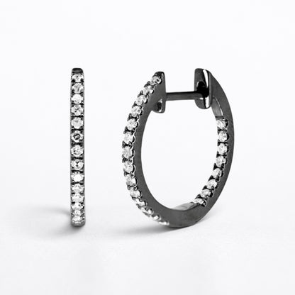 A pair of small hoop earrings with a dark metal finish and rows of clear diamonds, shown on a clean white background.