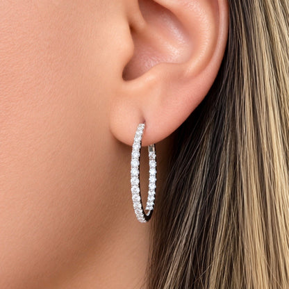 Close-up of a model wearing a 1-inch natural diamond inside-out hoop earring in solid 18K white gold.