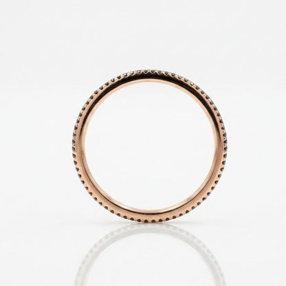 A rose gold ring with a textured beaded outer edge, shown on a clean white reflective surface.