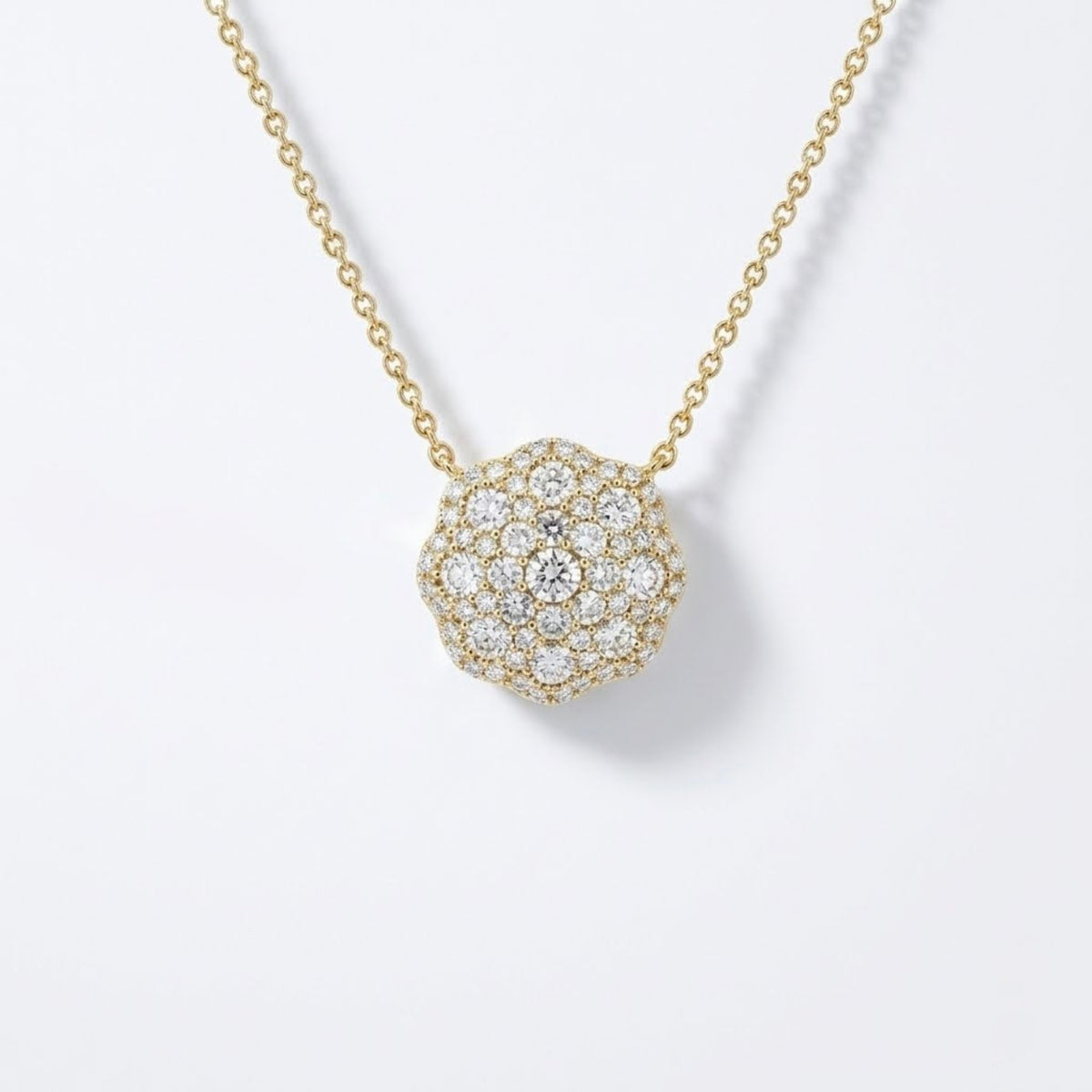 A gold chain necklace with a round pavé pendant set with clear diamonds, shown on a clean white background.