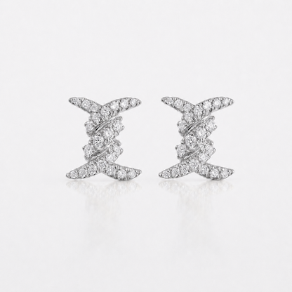 A pair of silver-toned stud earrings with a twisted, layered design set with small clear diamonds, displayed on a clean white background with a soft reflection.