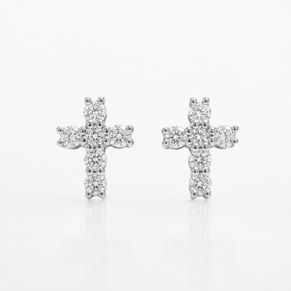 Pair of white gold natural diamond cross stud earrings on reflective surface