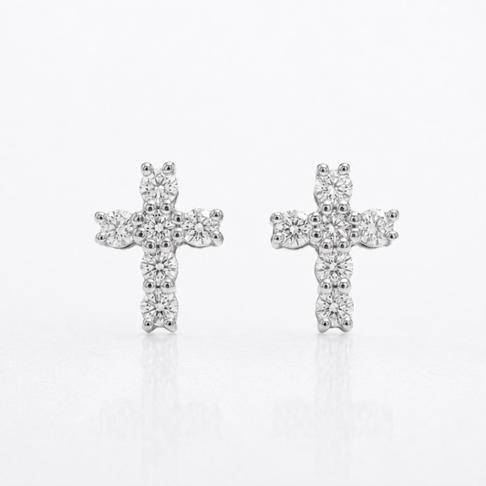 A pair of silver cross stud earrings set with small clear round-cut diamonds, displayed on a clean white reflective surface.