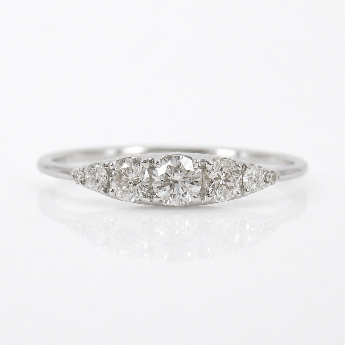 A silver-colored diamond ring with a marquise-shaped cluster setting featuring a central round diamond and three smaller diamonds on either side, set against a clean white background with a soft reflection.