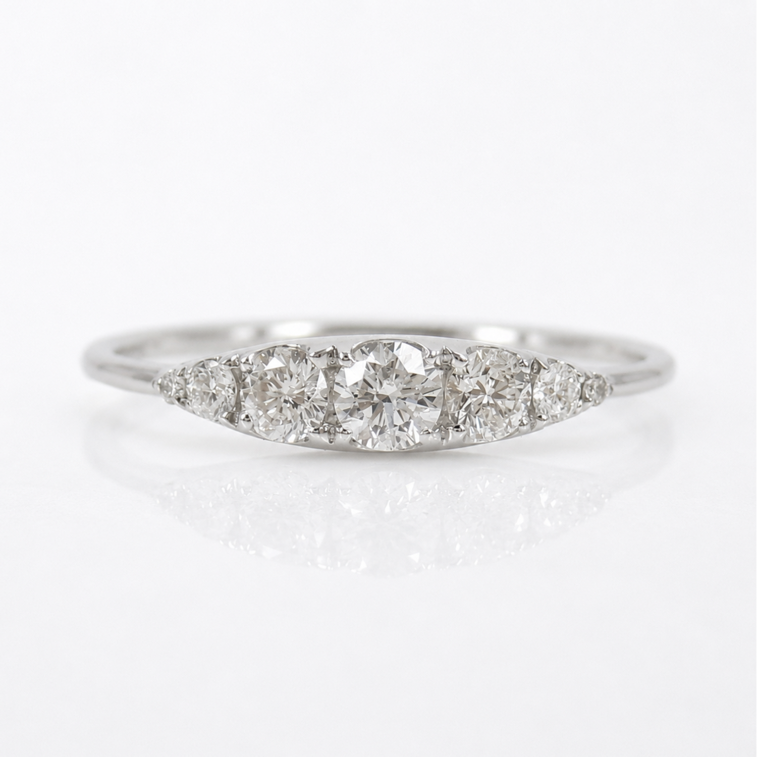 A silver-colored diamond ring with a marquise-shaped cluster setting featuring a central round diamond and three smaller diamonds on either side, set against a clean white background with a soft reflection.