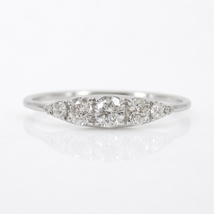 A silver-colored diamond ring with a marquise-shaped cluster setting featuring a central round diamond and three smaller diamonds on either side, set against a clean white background with a soft reflection.