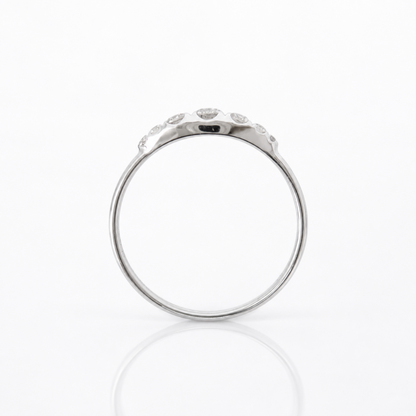 A silver-toned ring with a row of small clear diamonds along the upper band, photographed on a clean white background with a soft reflection below.