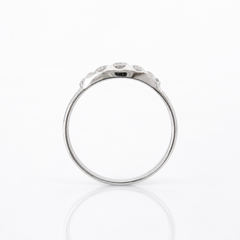 A silver-toned ring with a row of small clear diamonds along the upper band, photographed on a clean white background with a soft reflection below.