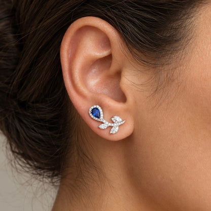 Close-up of model ear wearing natural blue sapphire and diamond floral ear climber earrings in 18K white gold