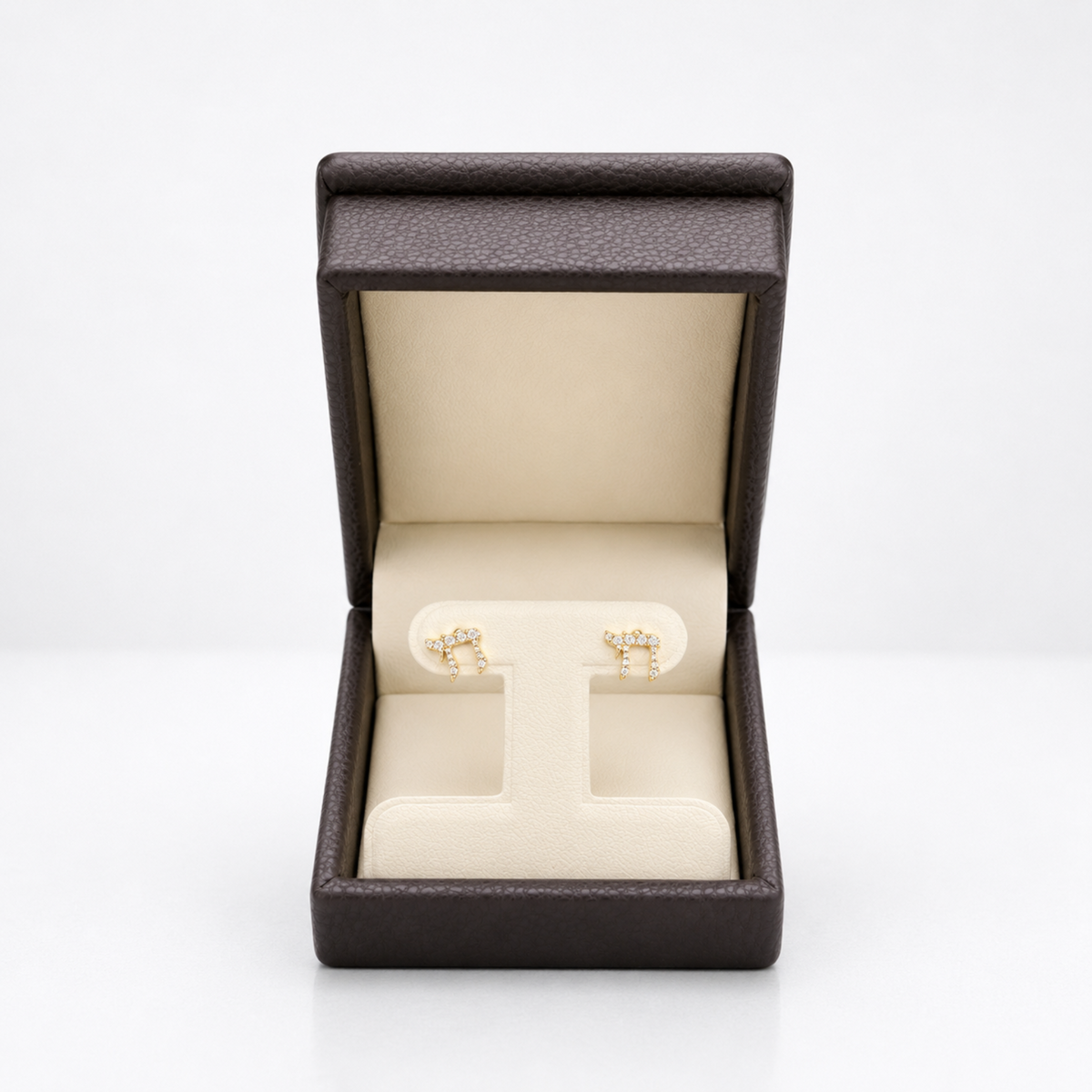 A pair of gold post earrings displayed on a cream jewelry stand inside an open dark brown textured presentation box on a white background.