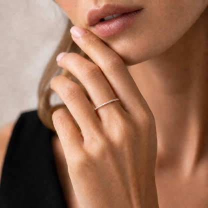 A close-up lifestyle shot of a woman wearing a delicate, thin silver band ring with a row of small diamonds on her ring finger.