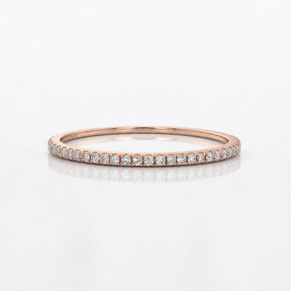 A rose gold eternity ring set with small round diamonds, shown on a clean white reflective surface.