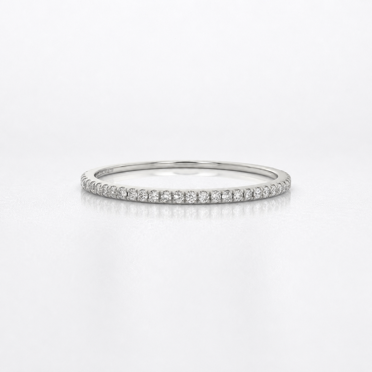 A thin silver diamond eternity ring with a continuous row of small round-cut diamonds on a polished band, shown against a clean white background.