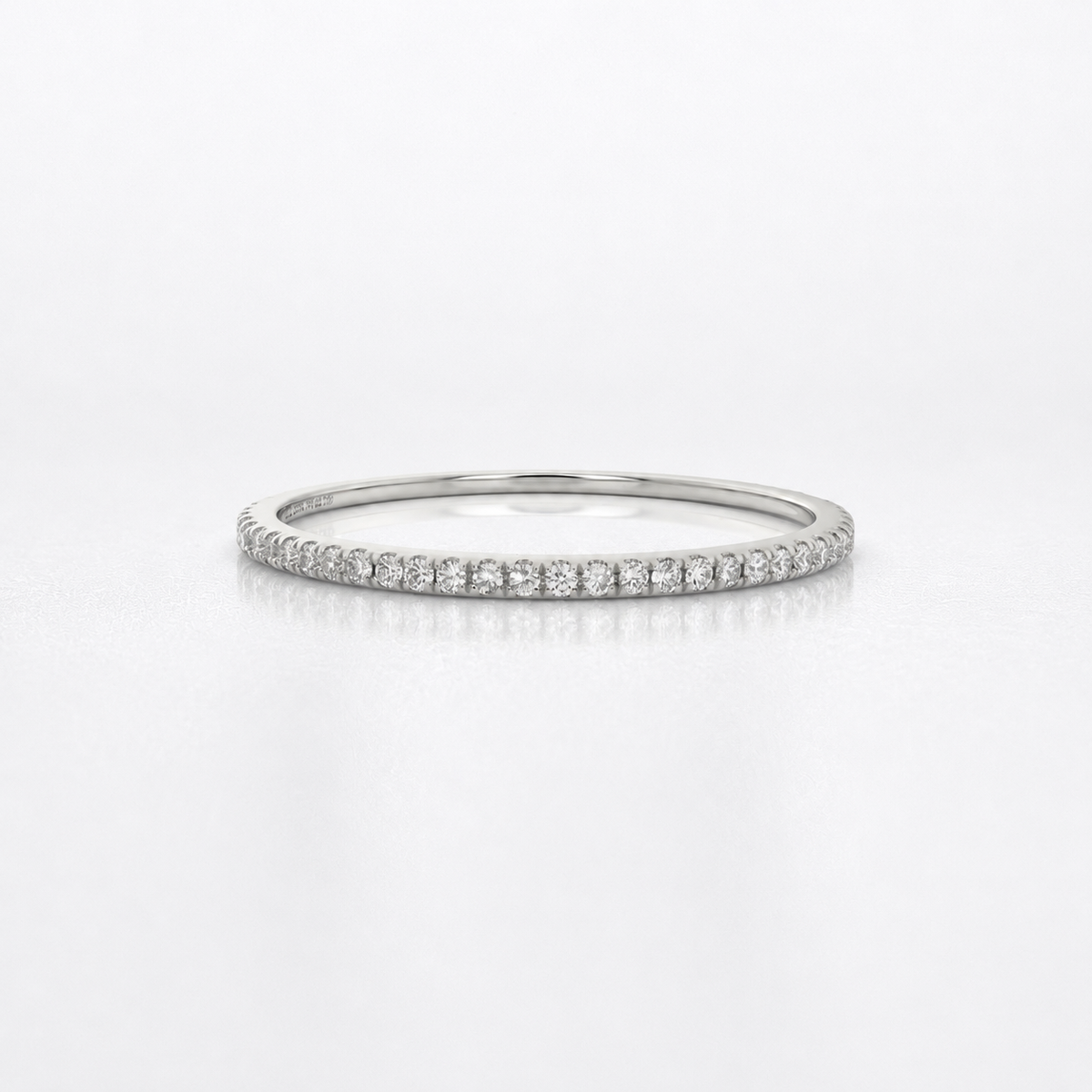 A thin silver diamond eternity ring with a continuous row of small round-cut diamonds on a polished band, shown against a clean white background.