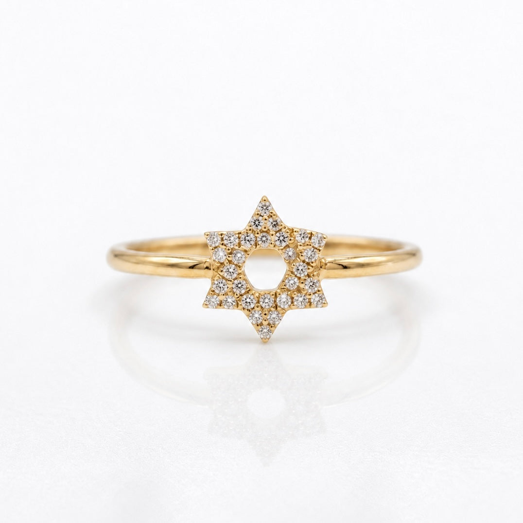 A gold ring featuring a six-pointed star pavé-set with small clear diamonds, shown on a clean white reflective surface.