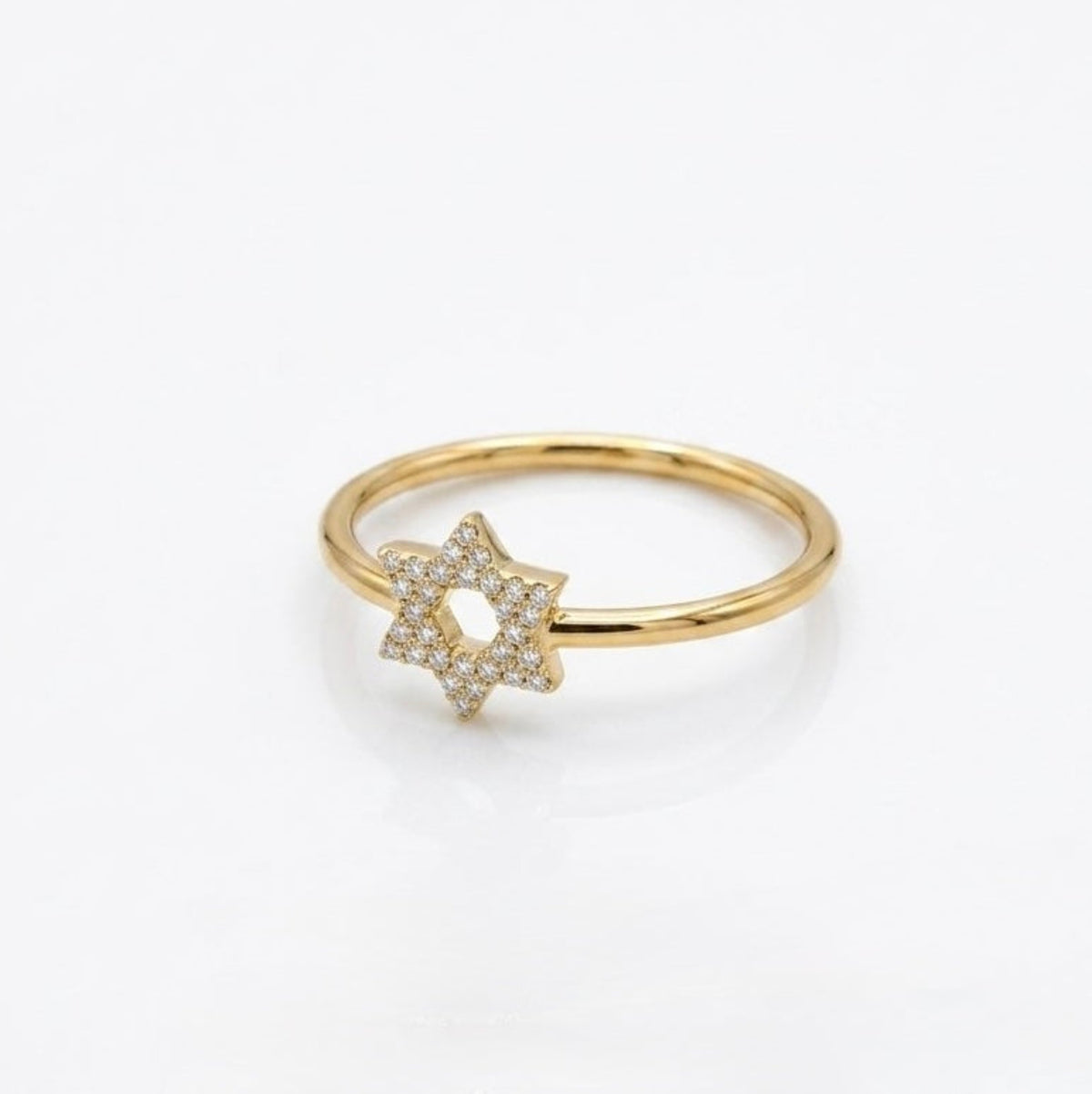A delicate gold ring featuring a pavé-set Star of David charm, photographed on a clean white background.
