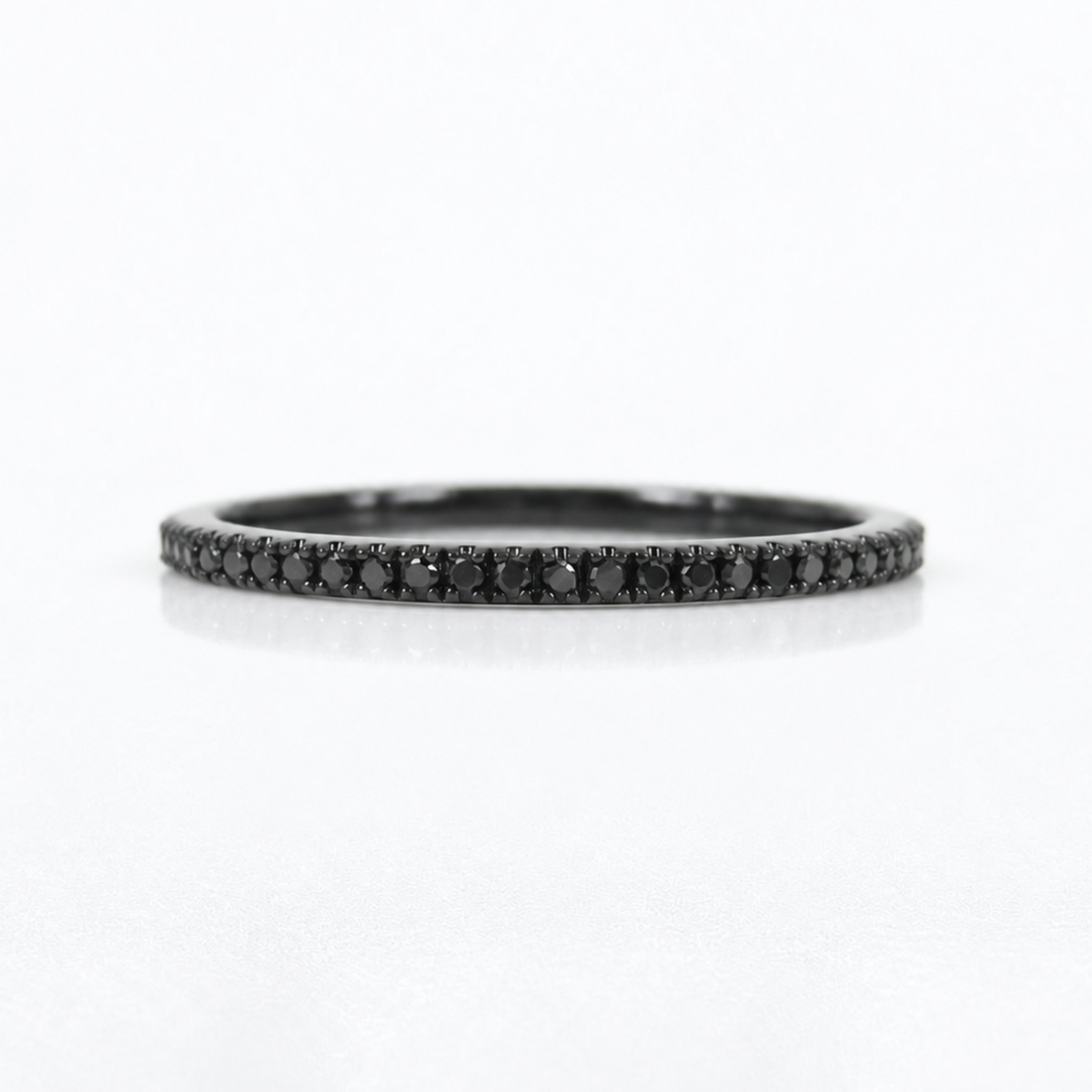 A slim black band ring paved with small black diamonds, centered on a clean white background.