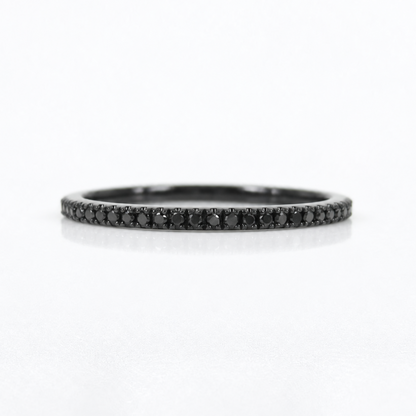 A slim black band ring paved with small black diamonds, centered on a clean white background.