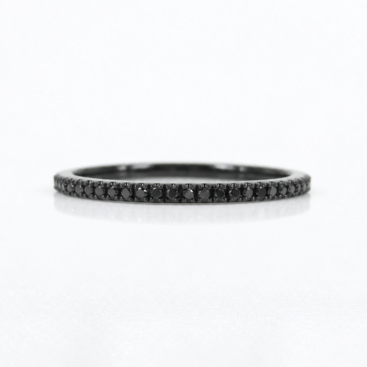 A slim black band ring paved with small black diamonds, centered on a clean white background.
