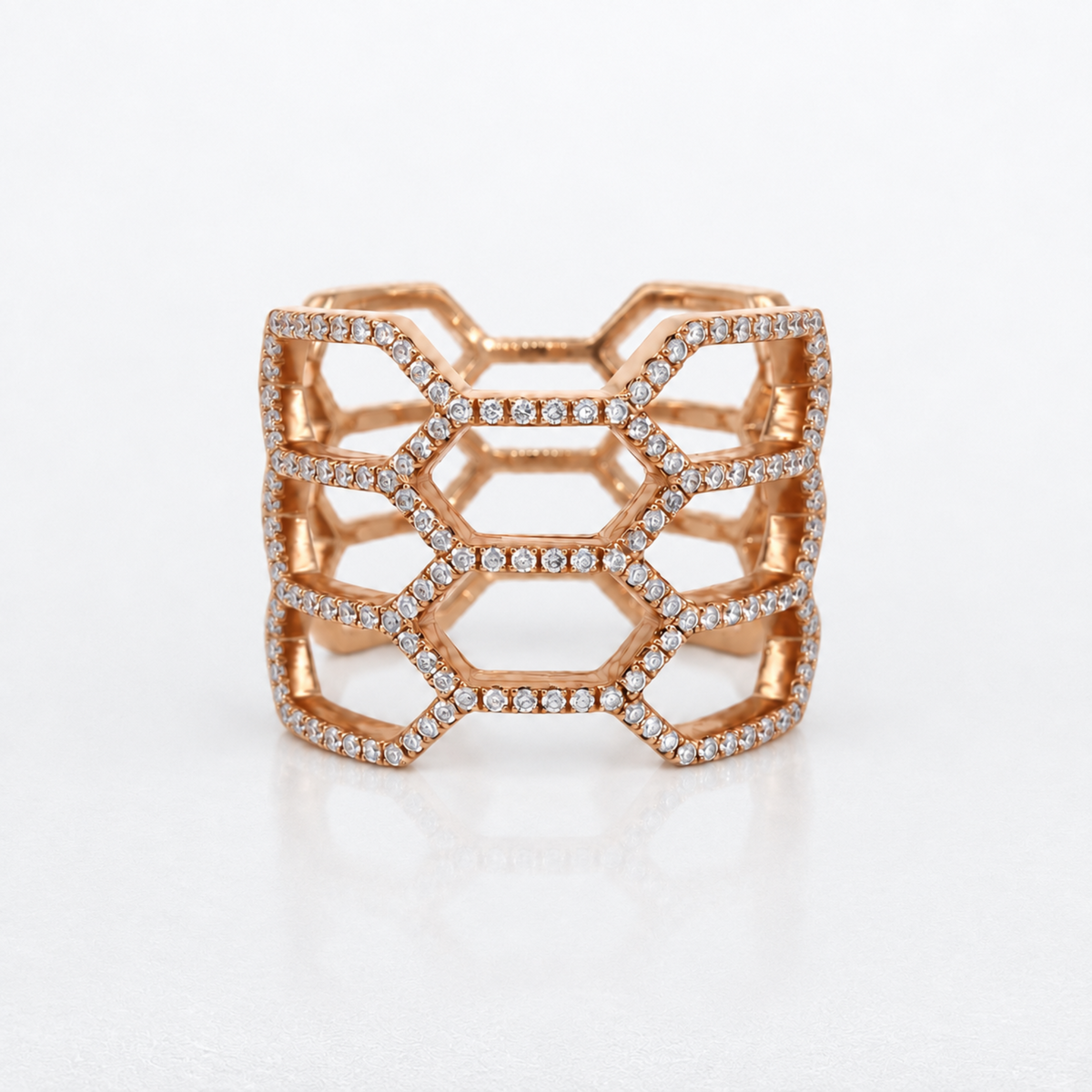 A rose gold geometric ring with a honeycomb lattice design, embellished with small pavé-set diamonds, shown on a clean white background.