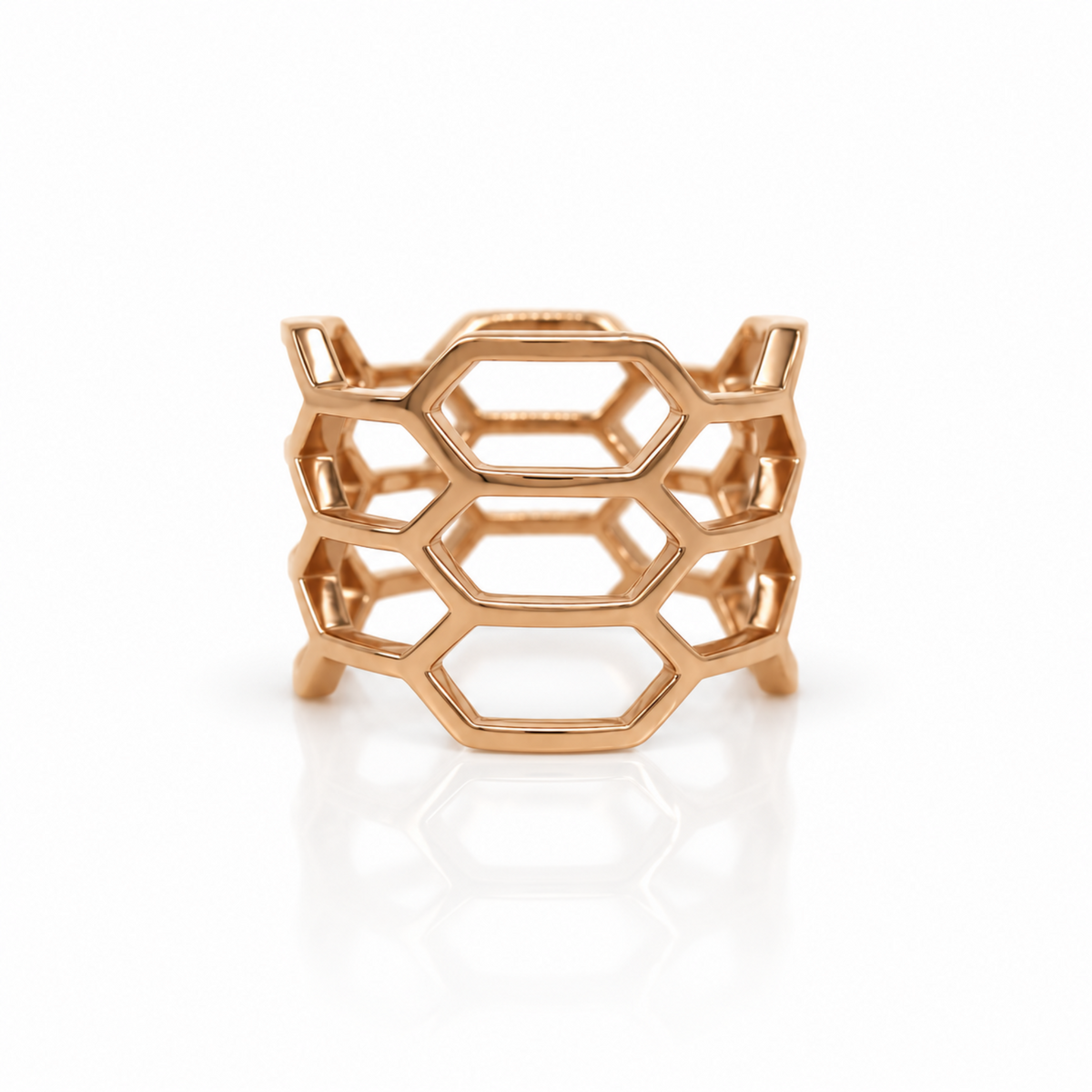 A rose gold geometric ring with an open honeycomb-like hexagonal design, shown on a clean white background with a soft reflection.