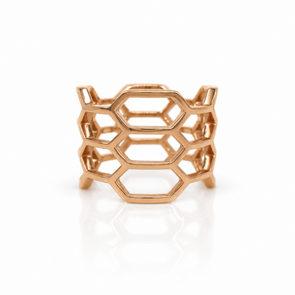 A rose gold geometric ring with an open honeycomb-like hexagonal design, shown on a clean white background with a soft reflection.