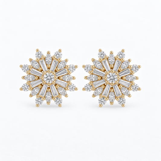 A pair of gold snowflake stud earrings set with clear baguette and round-cut diamonds, displayed on a clean white background.