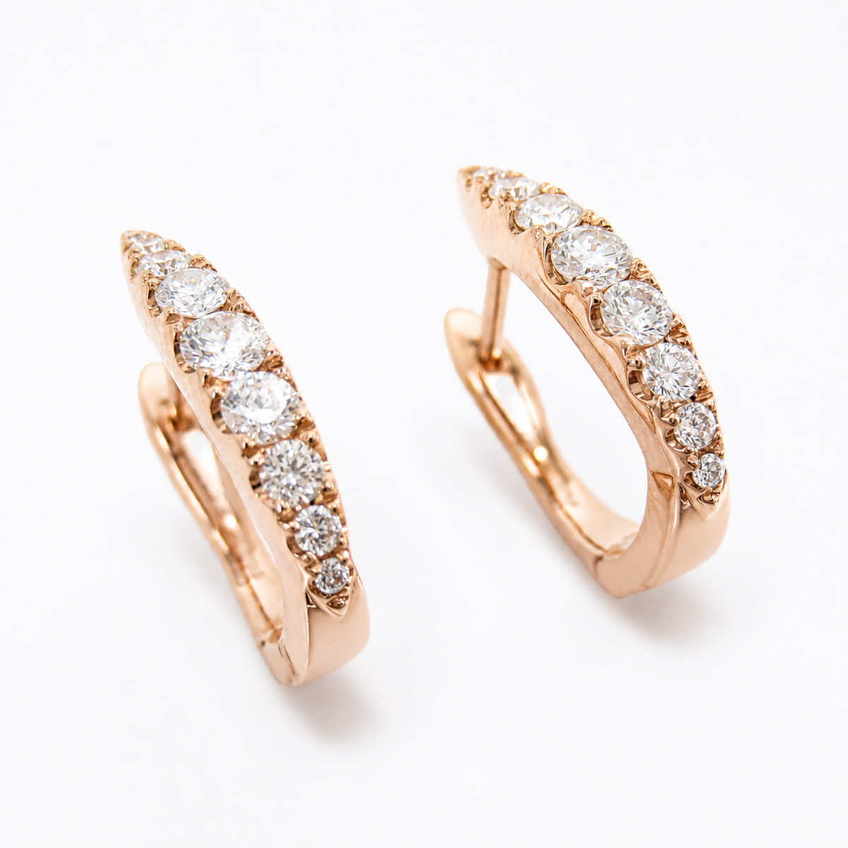 A pair of rose gold huggie hoop earrings set with round-cut diamonds, shown on a clean white background.