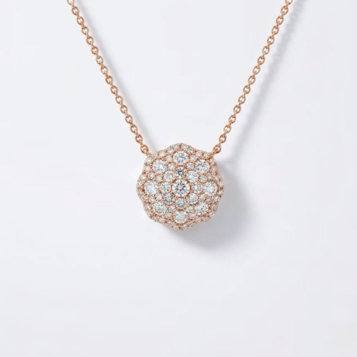 A rosevgold chain necklace with a round pavé pendant set with clear diamonds, shown on a clean white background.