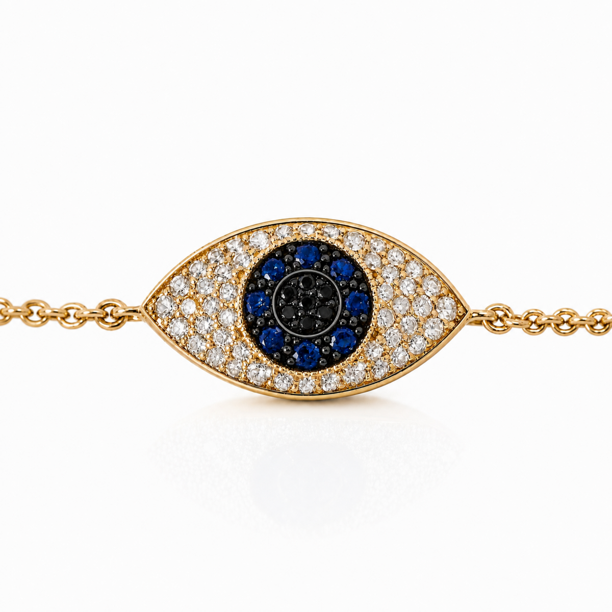 Gold-tone evil eye charm bracelet with a pavé diamond-encrusted outer eye, a black center, and a ring of blue gemstones around the middle, shown on a white background.