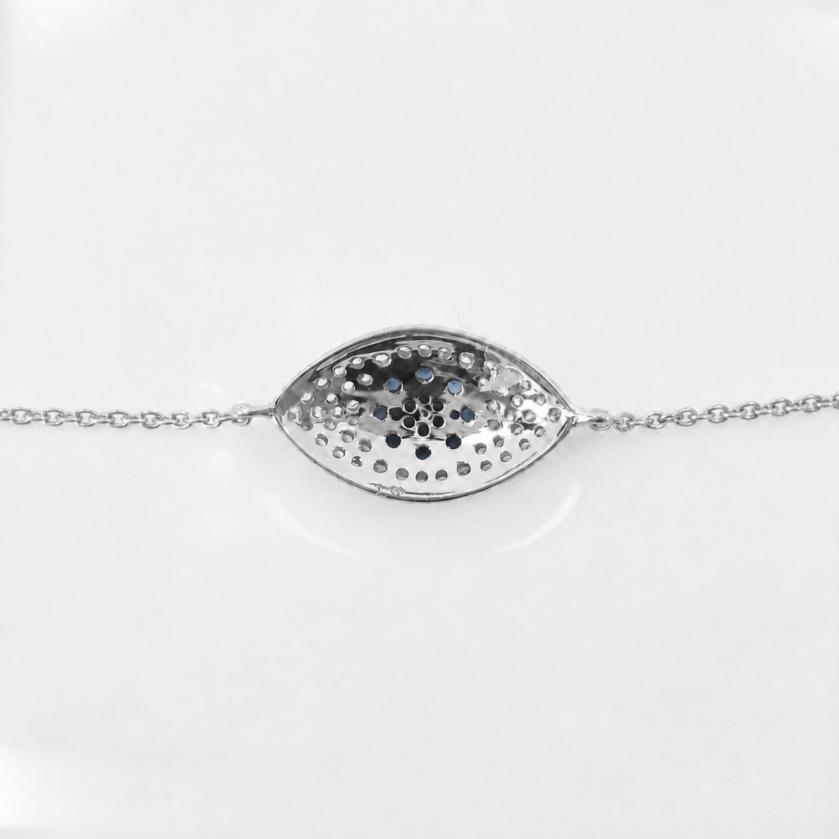 A silver chain bracelet featuring a hammered, textured oval pendant with a central blackened or oxidized pattern, displayed on a clean white background.