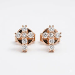 A pair of rose gold stud earrings featuring a cross-shaped cluster of clear round-cut diamonds, set against a plain white background.