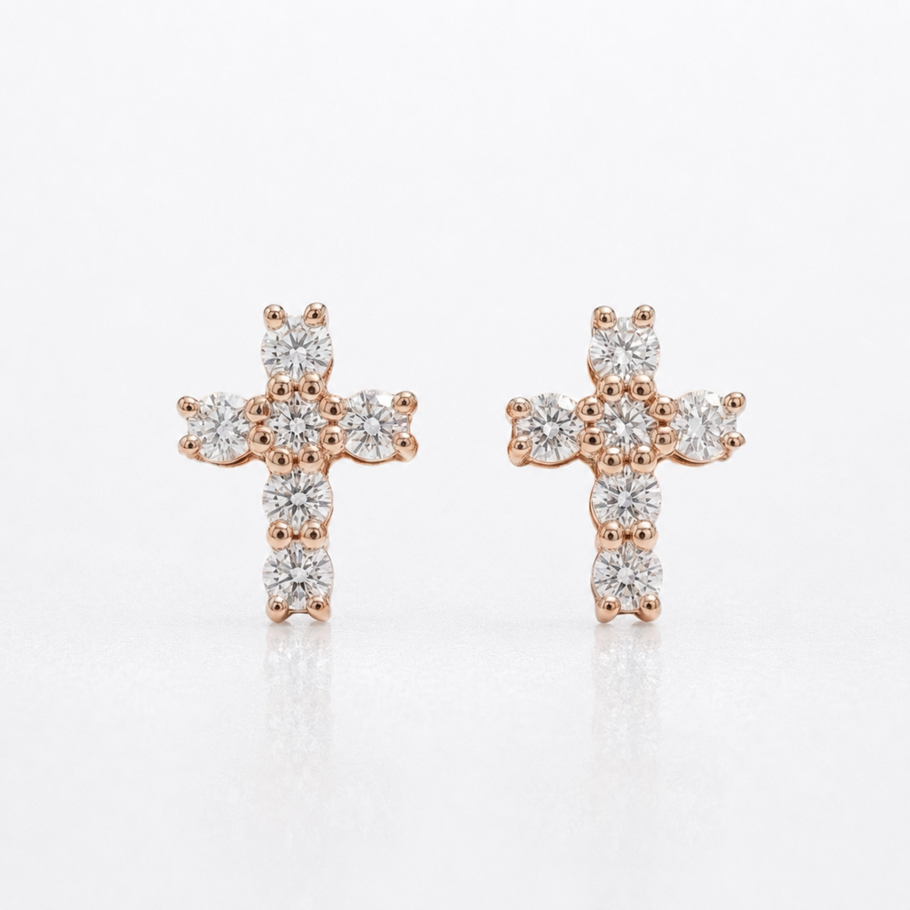 A pair of rose gold cross stud earrings set with clear round-cut diamonds, displayed on a clean white background with a soft reflection.