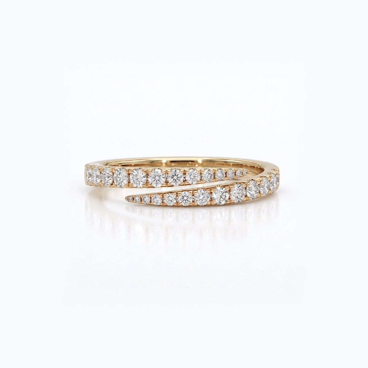 A yellow gold ring with pavé-set round diamonds, featuring a split design with one straight row and one curved row, shown on a clean white background with a soft reflection.