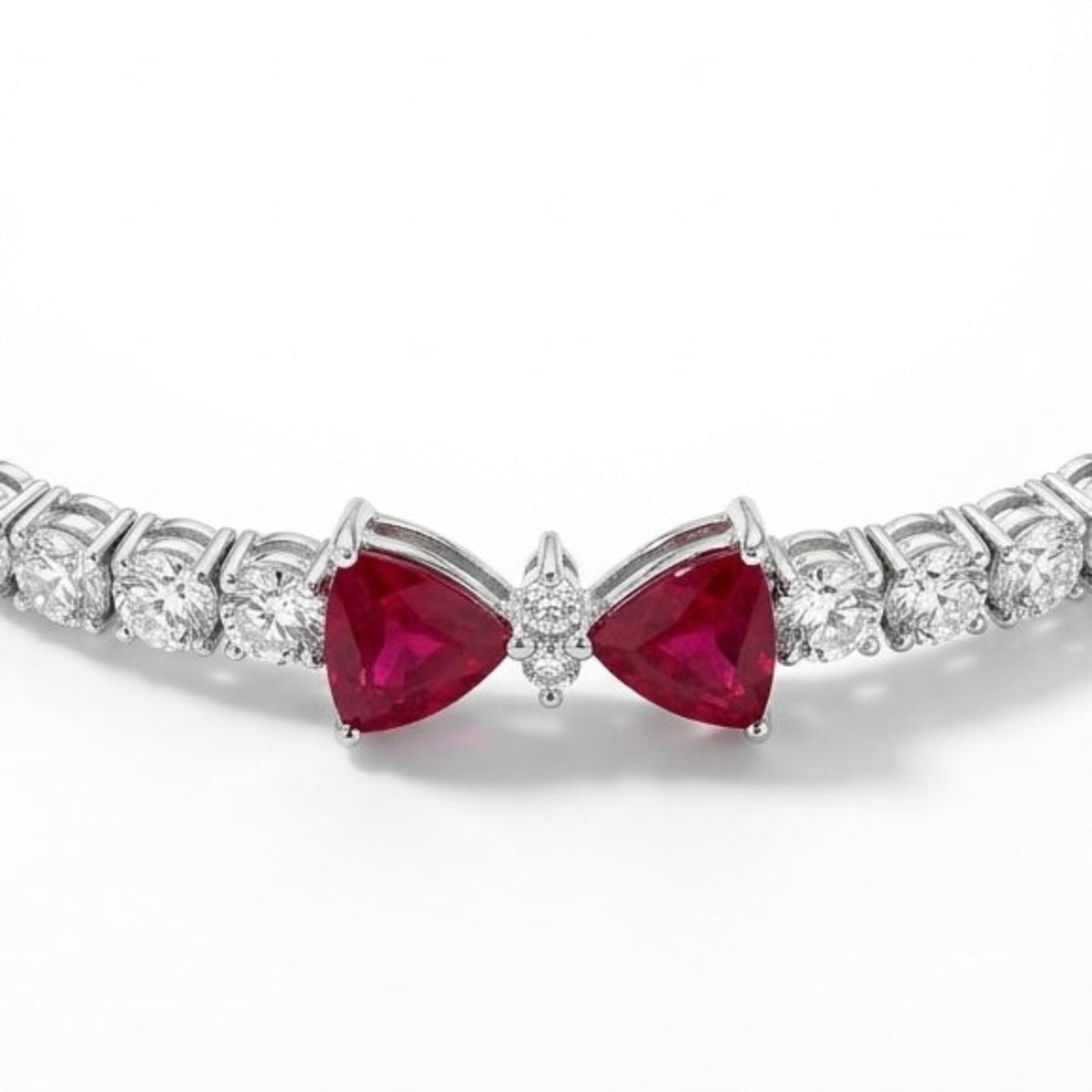 Close-up of natural trillion-cut ruby and diamond bow motif on 18K white gold tennis bracelet