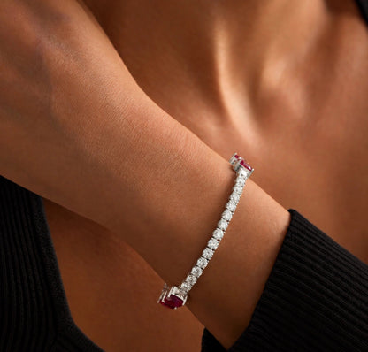 Angled view of 18K white gold natural ruby and diamond bow tennis bracelet on wrist